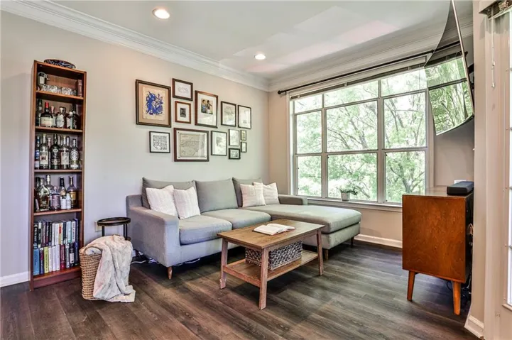 Recessed lighting, crown molding, large multi-pane window, and wood-finish flooring