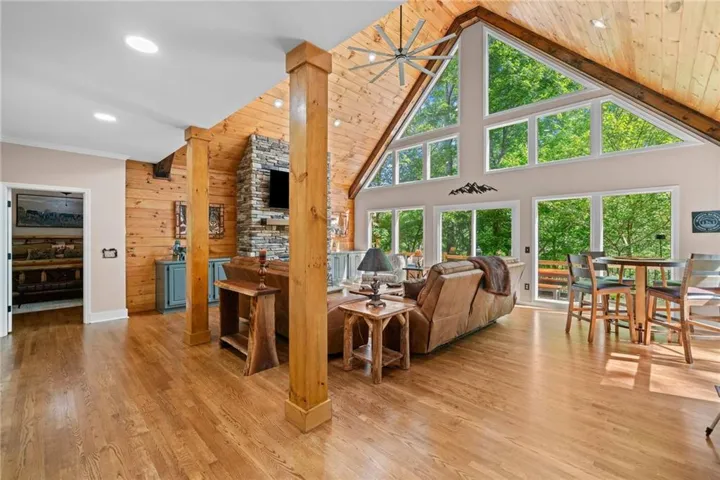 Living room featuring high vaulted ceiling, plenty of natural light, wood finished floors, a fireplace, and recessed lighting