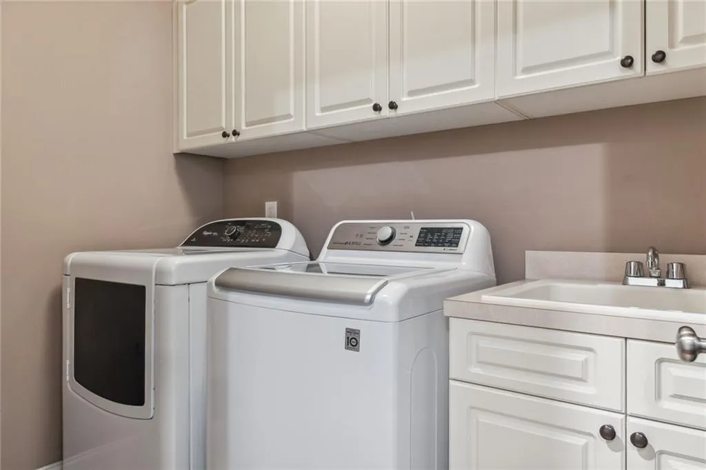 Laundry room includes  sink, cabinets, and washer and dryer