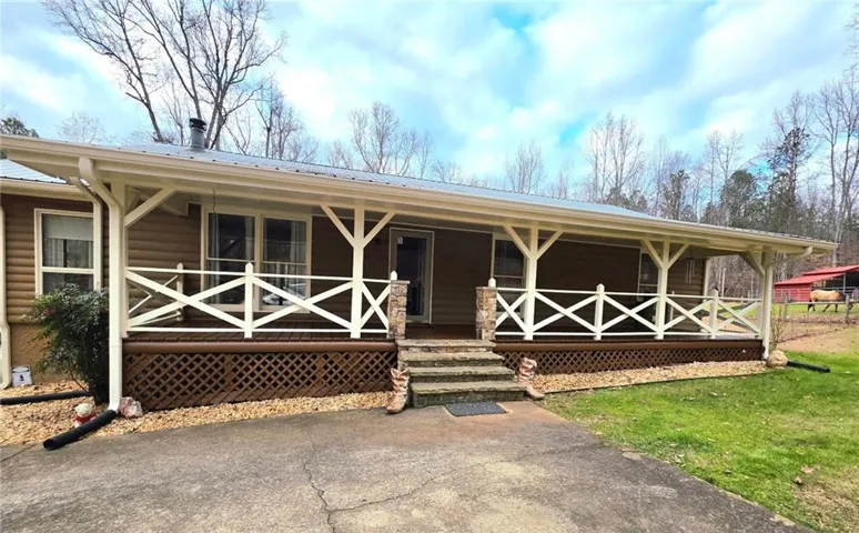 Expansive covered porch with decorative railing, stone-clad columns, and a metal roof