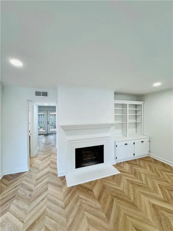 Unfurnished living room with baseboards, recessed lighting, a fireplace, and french doors
