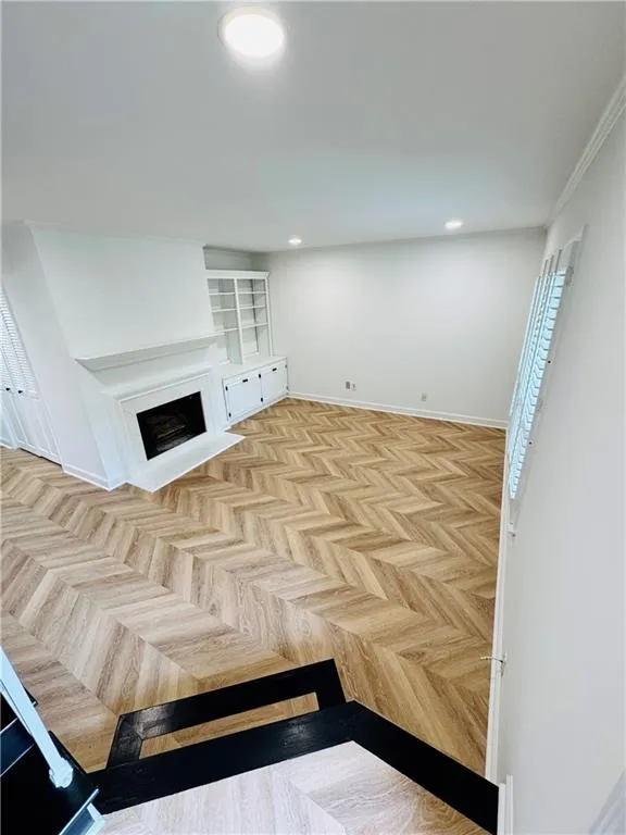 Unfurnished living room with a fireplace with flush hearth, recessed lighting, and baseboards