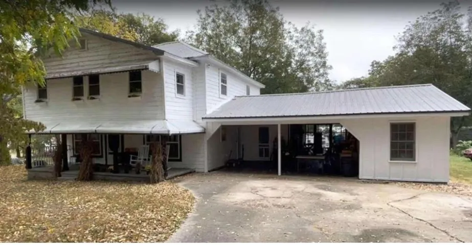 View of front of property with a carport, concrete driveway, and a metal roof