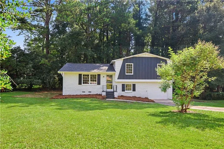 White brick exterior with dark gray siding, black shutters, and a dark shingle roof