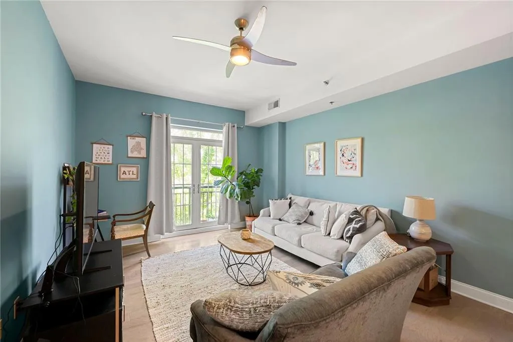 Living room with a ceiling fan, wood finished floors, and french doors
