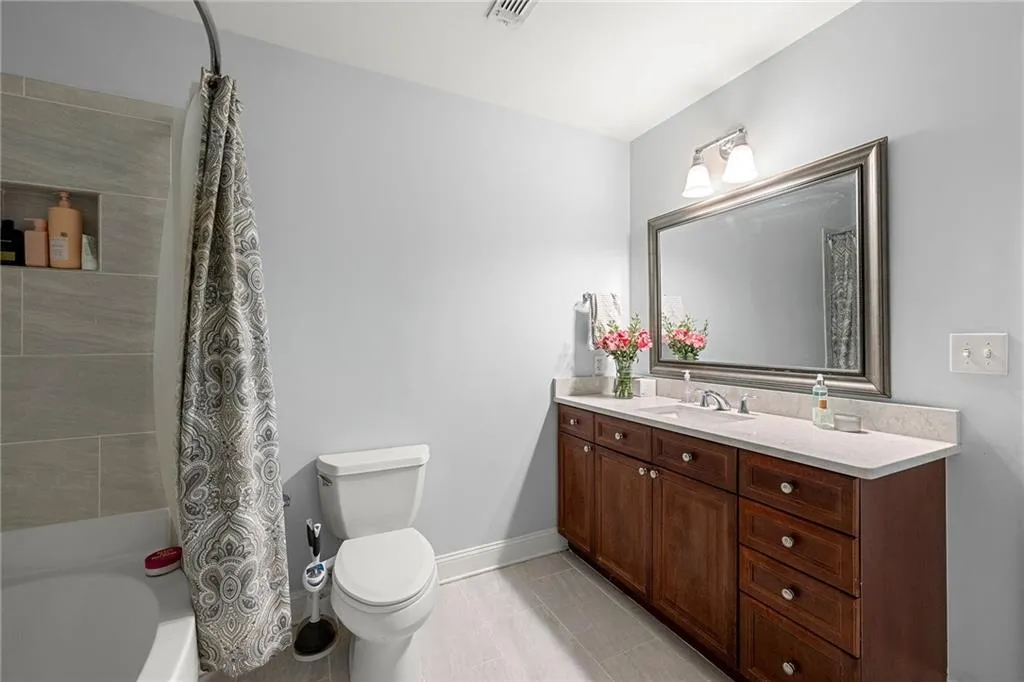 Full bathroom featuring shower / bath combination with curtain, vanity, and light tile patterned floors
