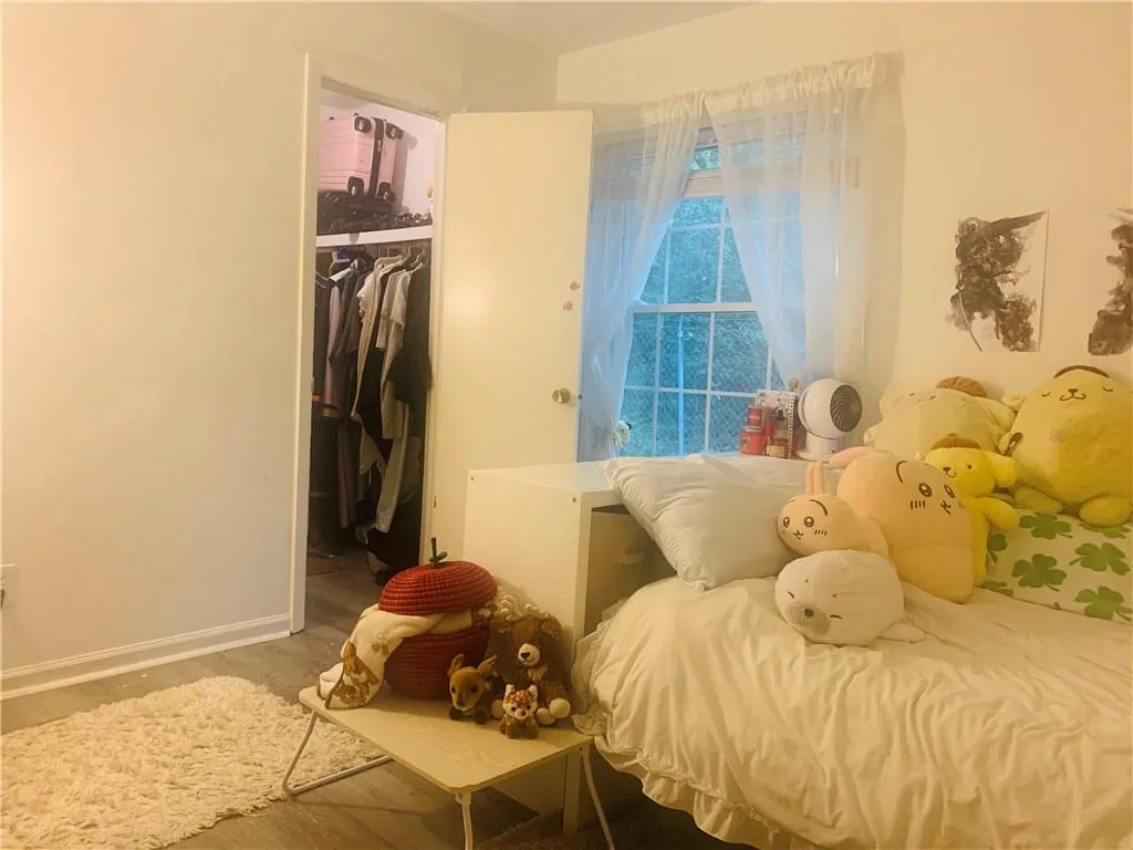 Bedroom with wood finished floors and a walk in closet