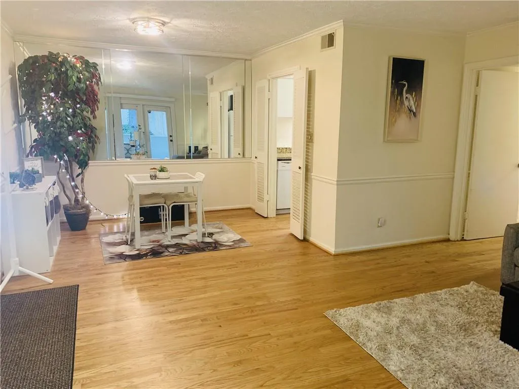 Dining area with a textured ceiling, light wood finished floors, and ornamental molding