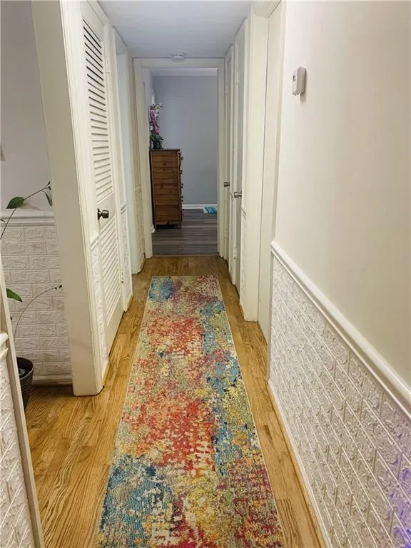 Corridor with light wood-style flooring and wainscoting