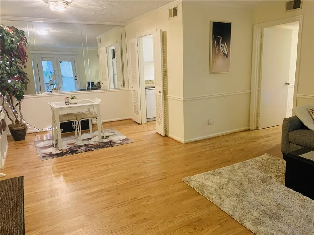 Living area featuring light wood finished floors, a textured ceiling, and ornamental molding
