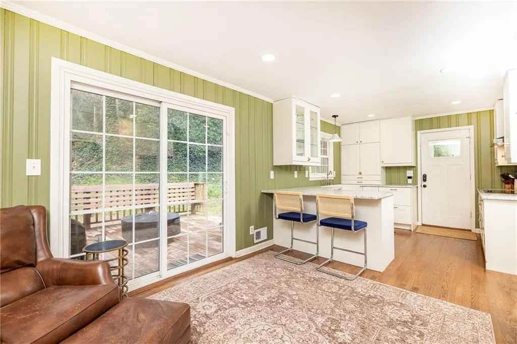 Kitchen with glass fronted cabinets, a peninsula, white cabinetry, a breakfast bar, and light wood-style flooring