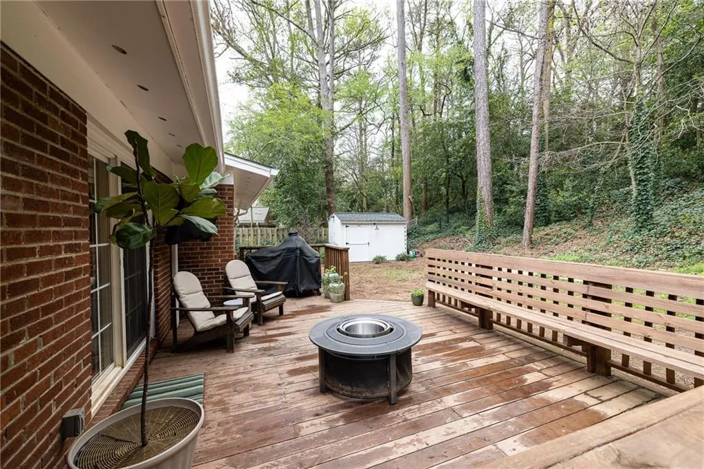 Wooden terrace with a fire pit, grilling area, and a storage unit