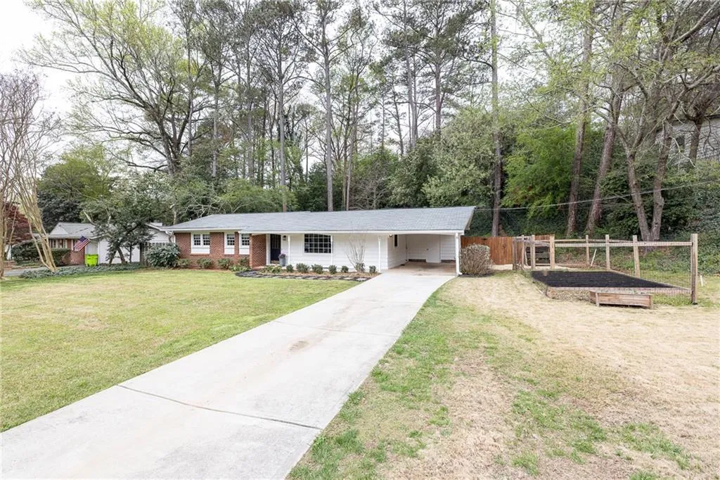 Single story home featuring an attached carport, concrete driveway, a porch, and view of scattered trees