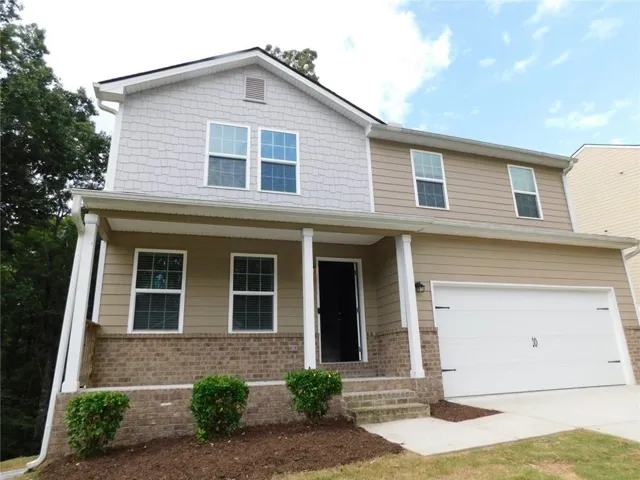 Two-story residence featuring brick and siding exterior, an attached garage, and a covered front porch with columns
