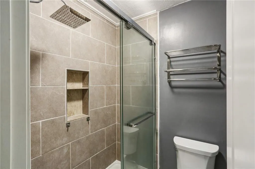 Tiled shower and dual shower heads including rainforest style and detachable sprayer.