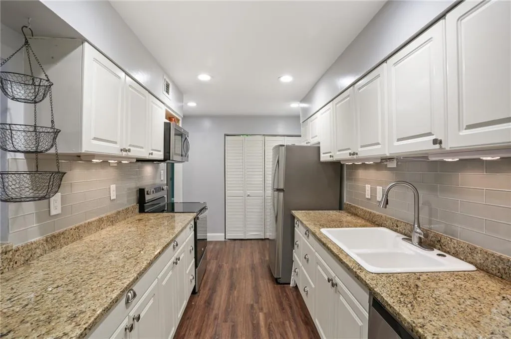 Kitchen with granite counters, tile backsplashes, farmhouse sink and under-cabinet lighting offers lots of storage and meal prep space.