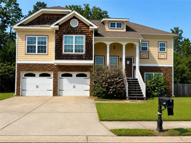 Two-story residence featuring a two-car garage, stone veneer accents, and a covered porch with columns