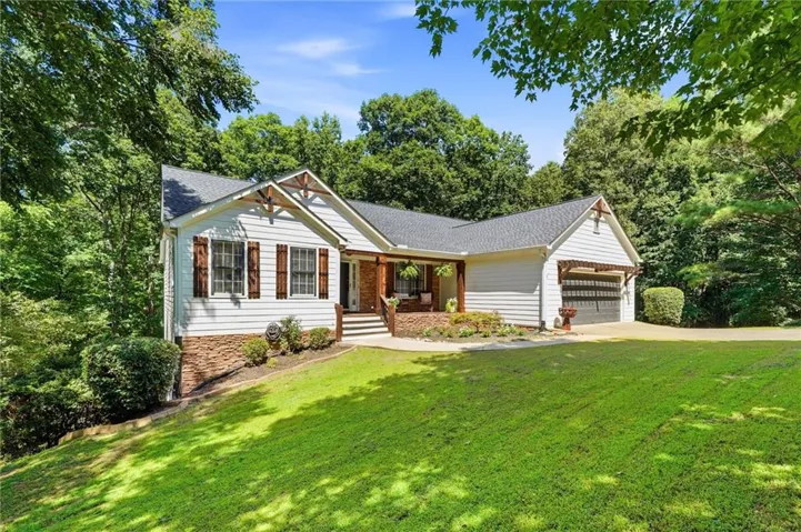 White siding residence with dark shingle roofing, featuring a covered front porch with exposed wood beams