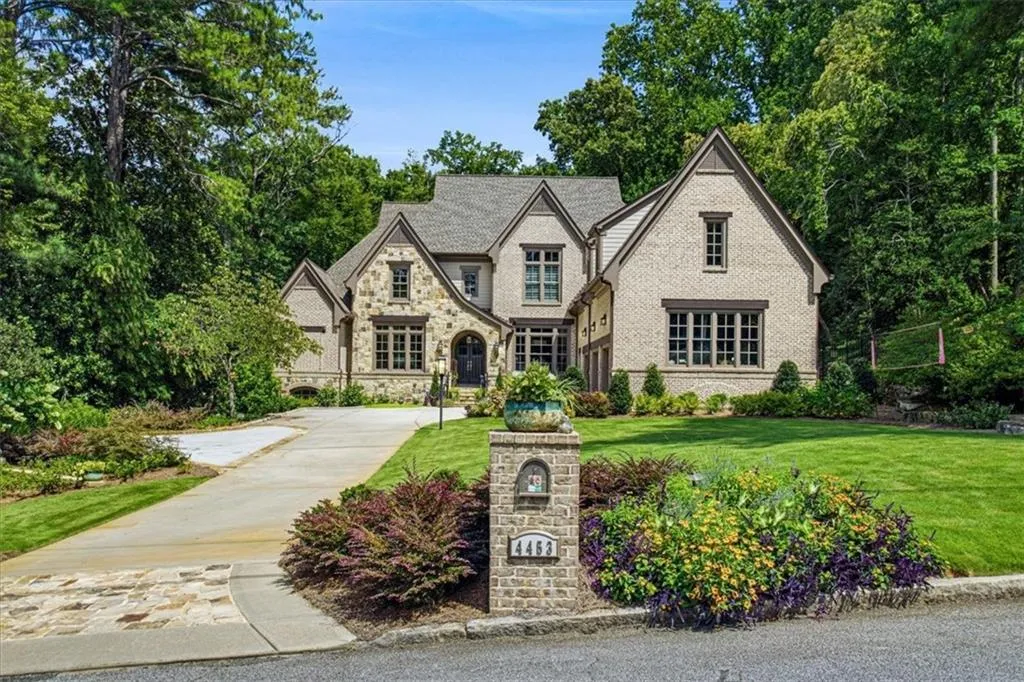 Stone and brick exterior with multiple gables, arched entry, and a prominent chimney