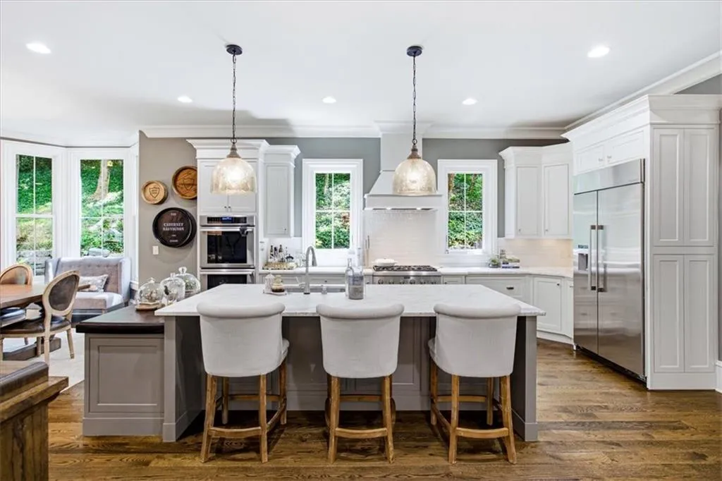 Well-appointed kitchen featuring white cabinetry, stainless steel appliances, a center island with countertop seating, and wood-finish flooring
