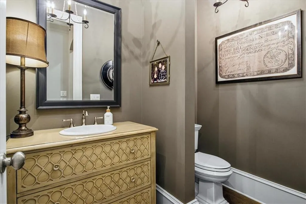 Vanity with decorative carved wood-finish drawers, oval undermount sink, and wall-mounted mirror