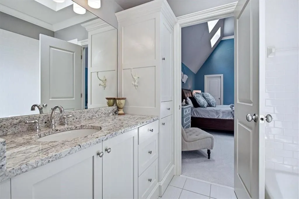 Vanity with an undermount sink, a stone-finish countertop, and white cabinetry