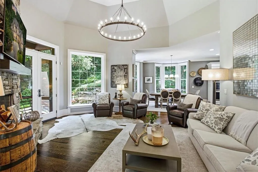 Vaulted ceilings, hardwood flooring, stone-clad fireplace, French doors, and a decorative chandelier