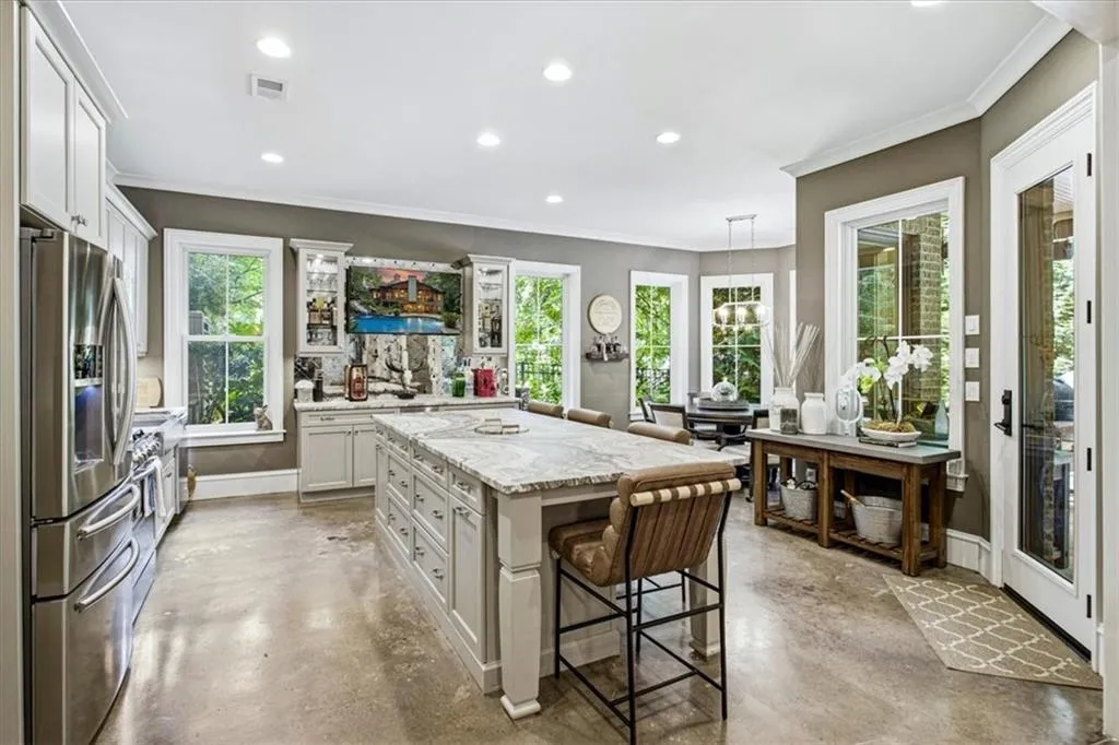 Kitchen featuring a large central island with seating, stainless steel appliances, white cabinetry, and multiple windows