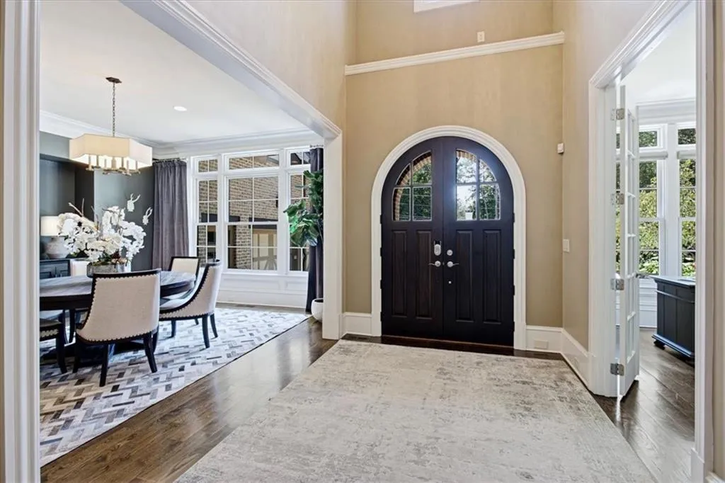 Arched double entry doors, wood-finish flooring, white trim, recessed lighting, and a drum pendant light fixture