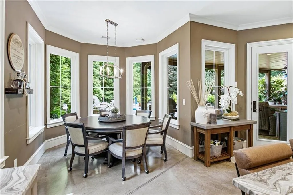 Sunlit sitting room with curved walls of multi-pane French doors and windows framing natural landscape views