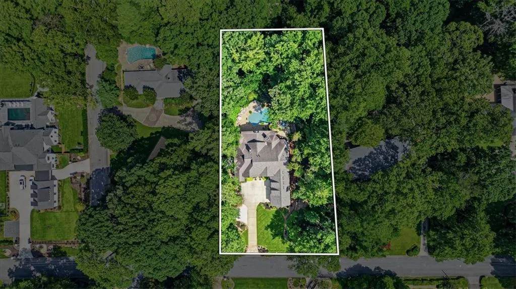 Expansive lot with mature trees, a private swimming pool, and a paved driveway