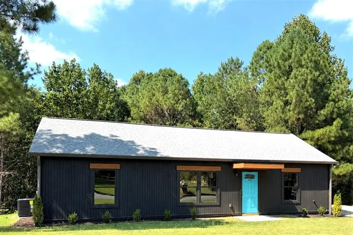 Contemporary exterior featuring vertical siding, a bright blue entry door, and wood-toned accent details