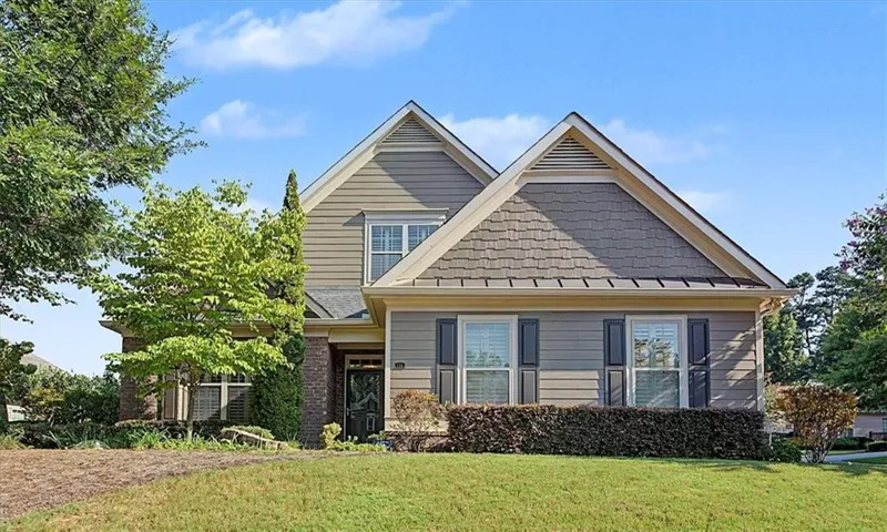 Gable roofline, mixed siding exterior, brick accents, dark shutters, and a manicured front lawn