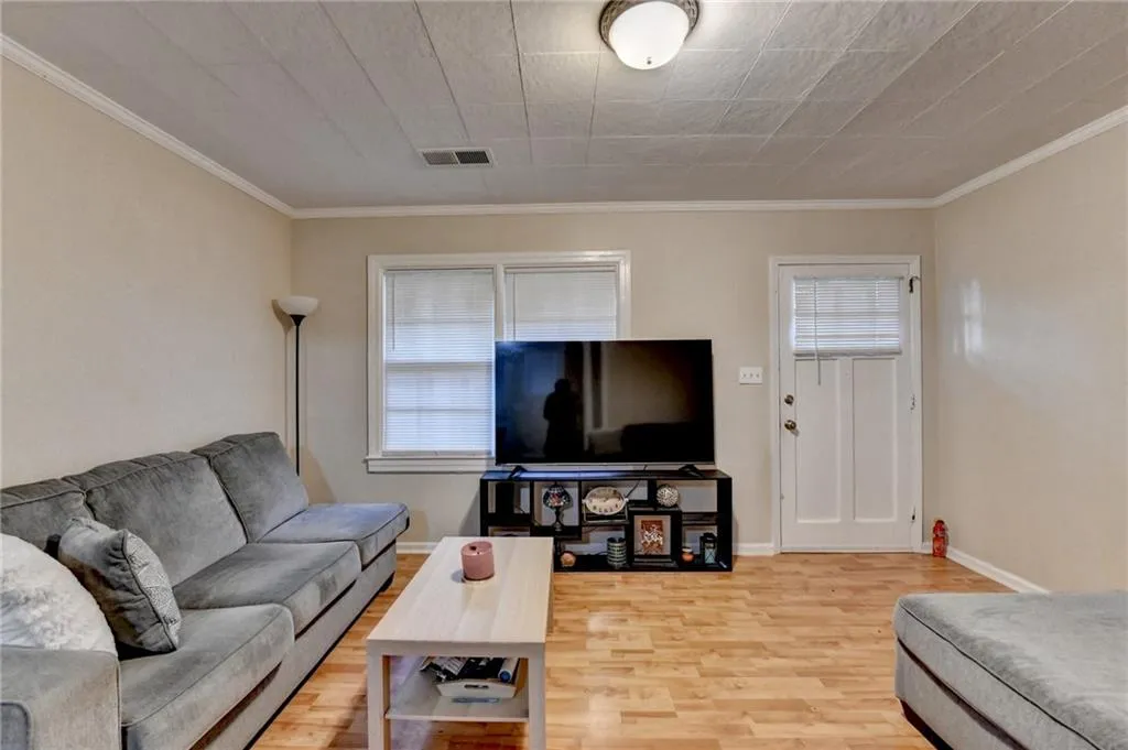 Living area with healthy amount of natural light, crown molding, and light wood-style floors
