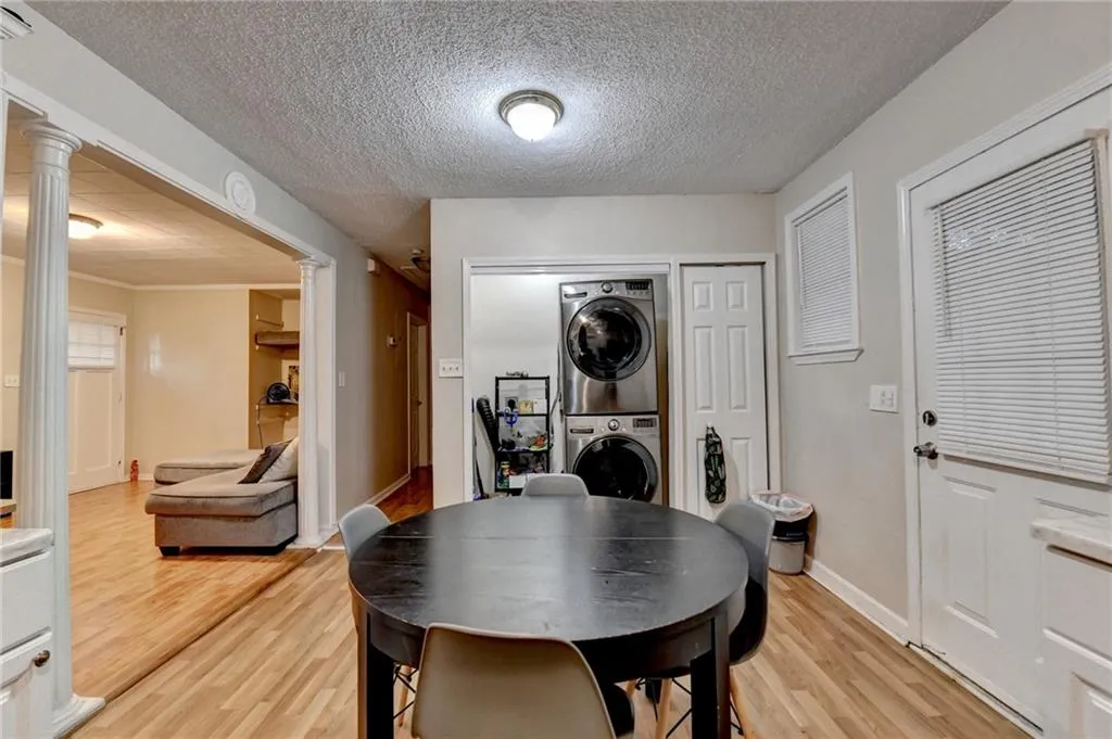 Dining area with light wood finished floors, a textured ceiling, and stacked washing machine and dryer