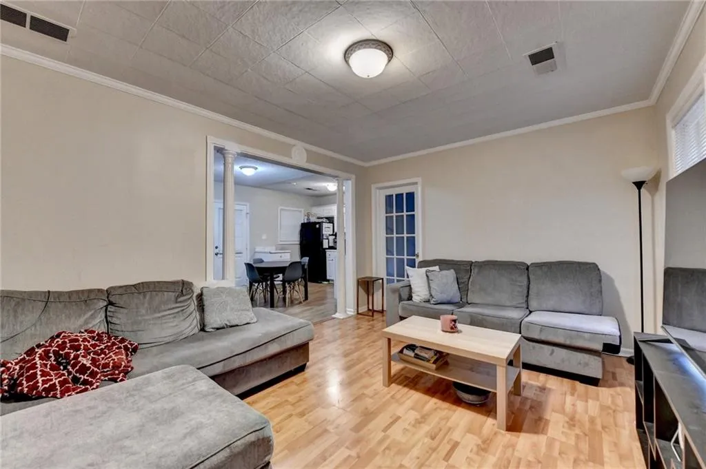 Living area with ornamental molding and light wood-style floors