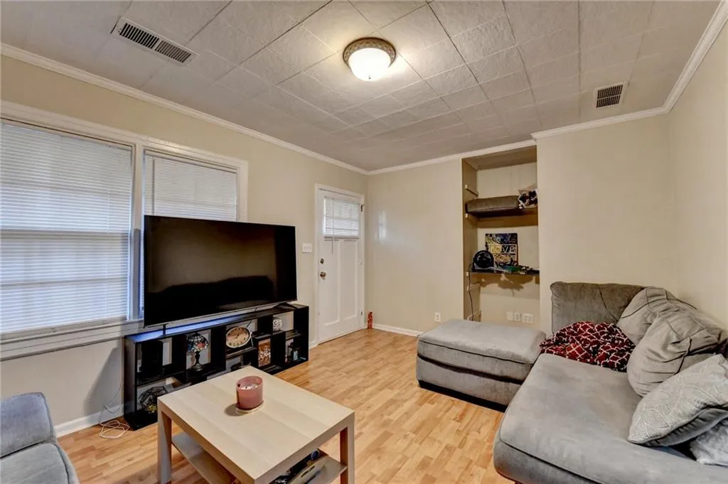 Living room featuring crown molding and light wood-style flooring