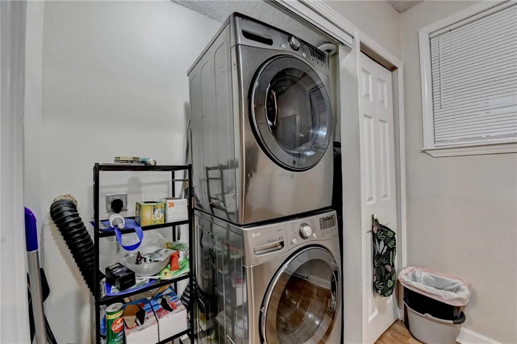 Laundry room featuring stacked washer / dryer and wood finished floors