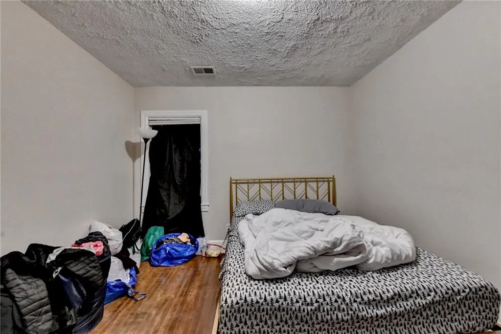Bedroom with wood finished floors and a textured ceiling