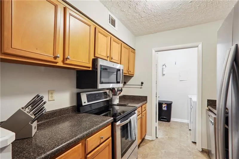 Kitchen with appliances with stainless steel finishes, light tile flooring, and a textured ceiling