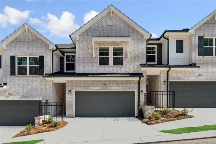Contemporary brick townhome community featuring clean-lined architecture with peaked gable rooflines, multi-pane windows with black trim, and three-car garage entries