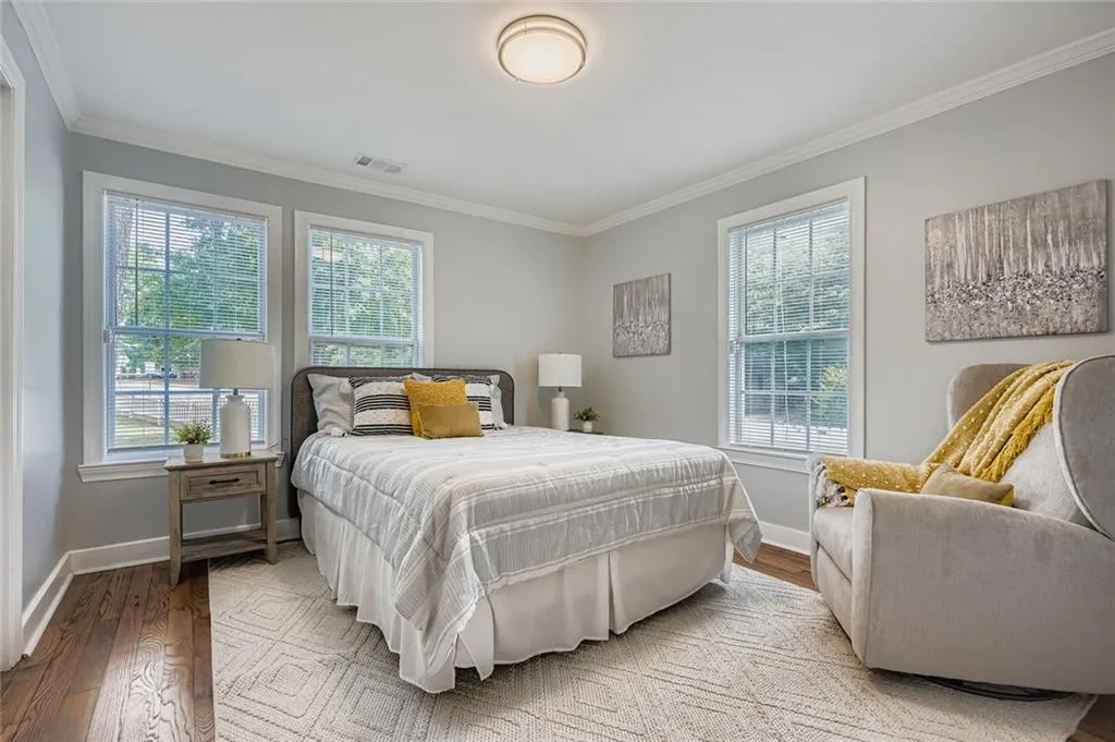Primary bedroom has plenty of windows, hardwood floors and appealing paint colors.