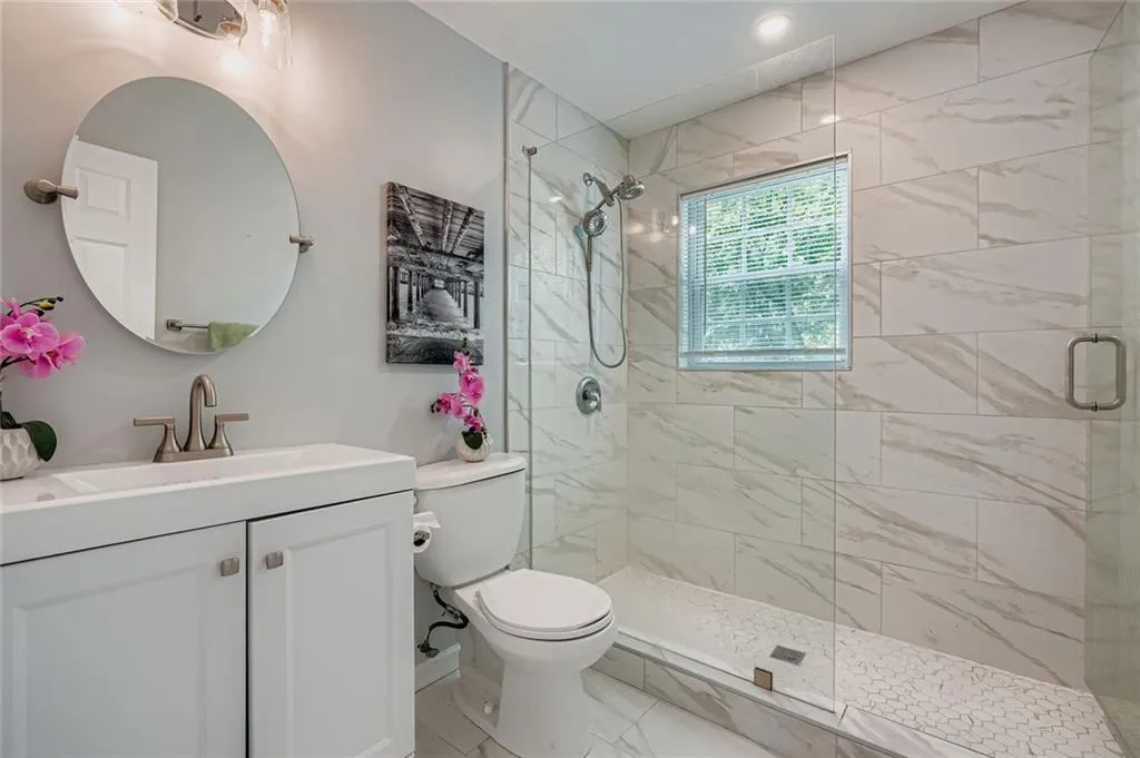 Main level bathroom is recently updated with white vanity, and a beautiful tile shower.