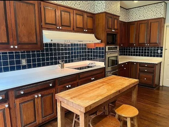 Kitchen with decorative backsplash, light countertops, and dark wood-type flooring