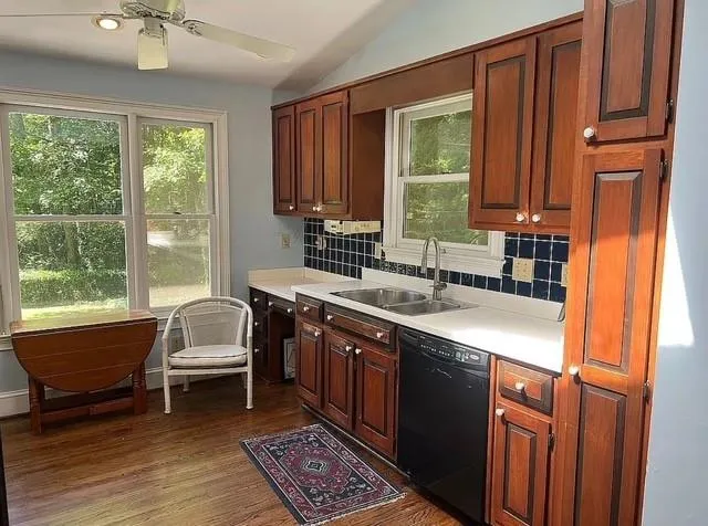 Kitchen featuring decorative backsplash, black dishwasher, light countertops, healthy amount of natural light, and vaulted ceiling