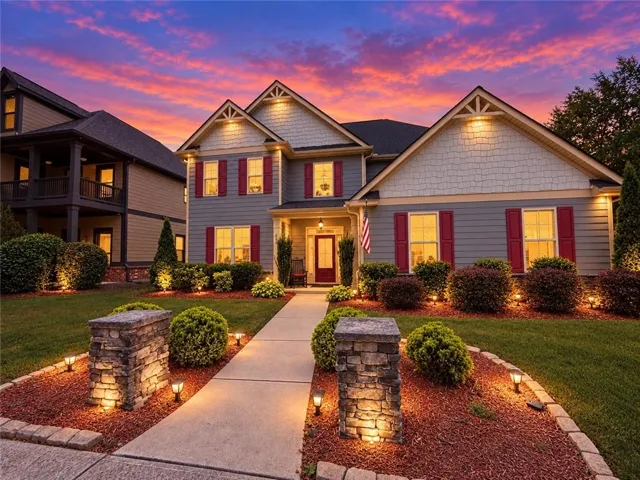Two-story residence featuring gabled rooflines, red window shutters, and exterior accent lighting