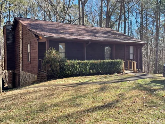 View of front of property with a front yard, a chimney, and a shingled roof