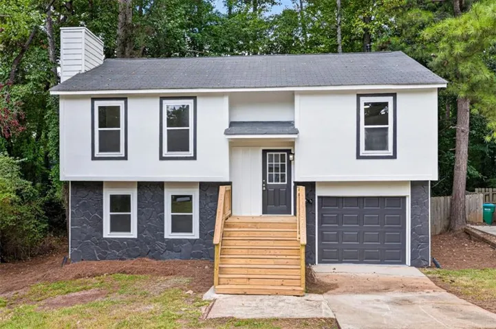 Two-story exterior with a contrasting façade, featuring a prominent chimney, new wood entry steps, and an attached single-car garage
