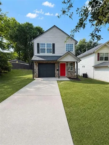 Two-story residence featuring light gray siding with dark shutters, a stone accent facade, and a vibrant red front door