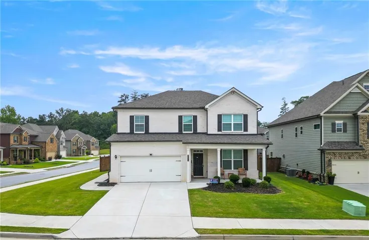 Two-story residence with a light-colored facade, dark roofing, and a front-facing attached garage